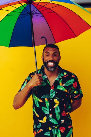 Black male smiling under colorful umbrella