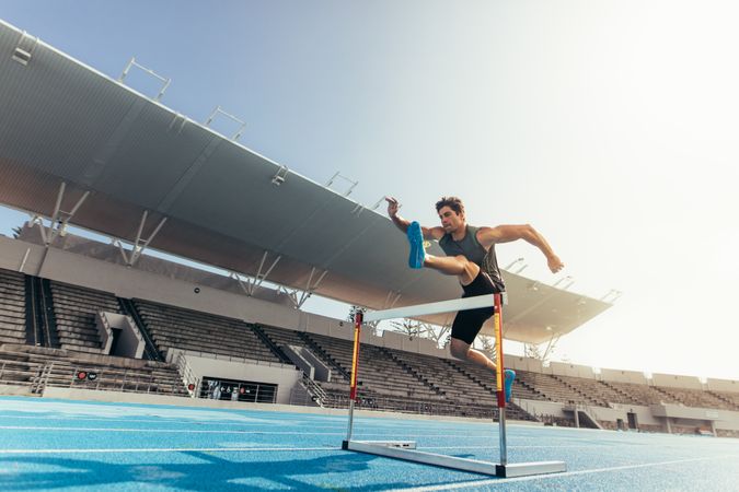 Athlete practicing hurdle jump on running track