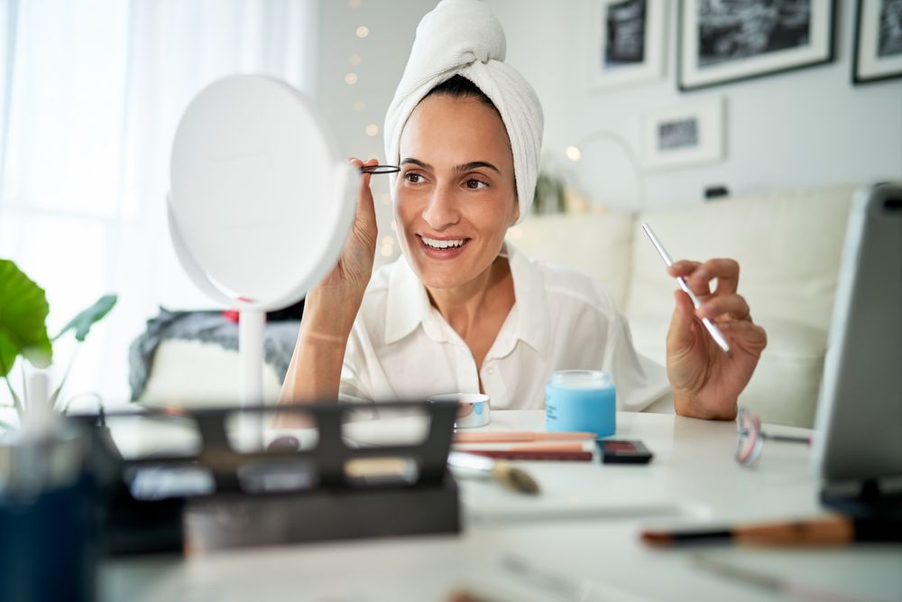Smiling woman shaping eyebrows with tweezers