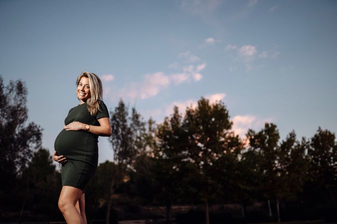 Charming pregnant woman standing on walkway in park