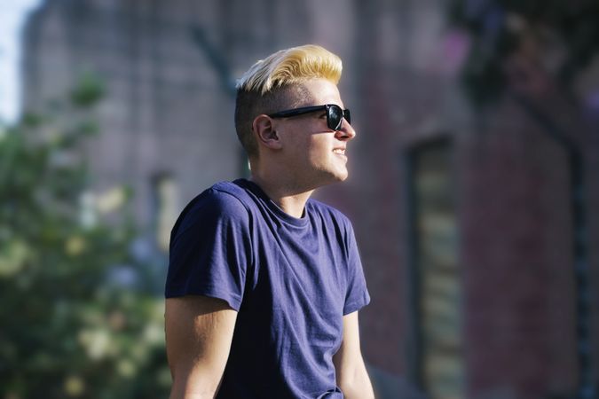 Side view of blond man with sunglasses looking away outdoors in the city
