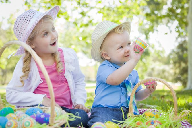 Cute Young Brother and Sister Enjoying Their Easter Eggs Outside