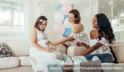 Female touching tummy of pregnant woman at baby shower 56GgwL