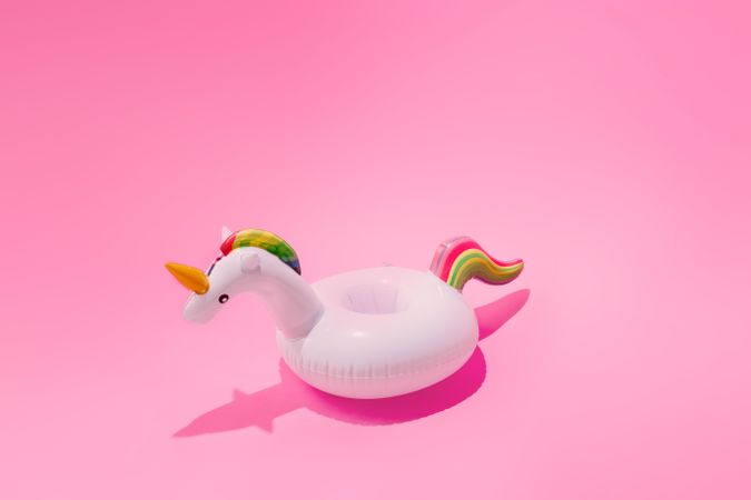 Inflatable unicorn pool toy on pastel pink background