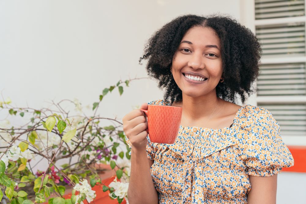 Woman sitting drinking coffee on the terrace of a house