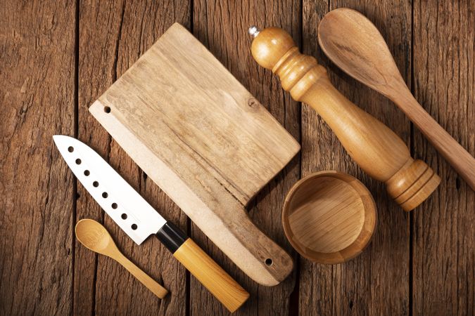 Cutting board with kitchen utensils on rustic background.