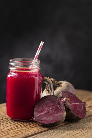 Red beet juice in a glass cup on the wooden table.