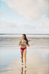 Woman in swimwear running near sea
