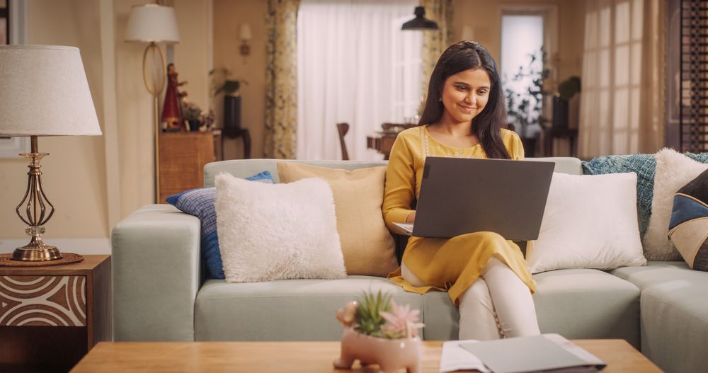 Focused Indian Woman Using Laptop Computer at Home: Engaging in Remote Work Tasks, Sending Emails, or Managing Projects