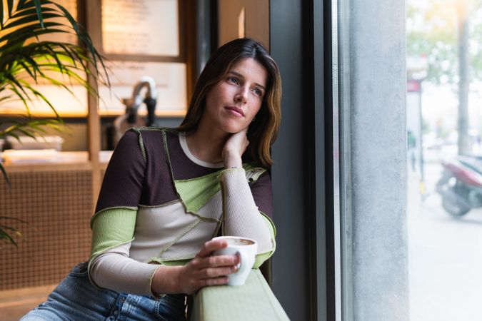 Pensive woman with cup of coffee in cafe