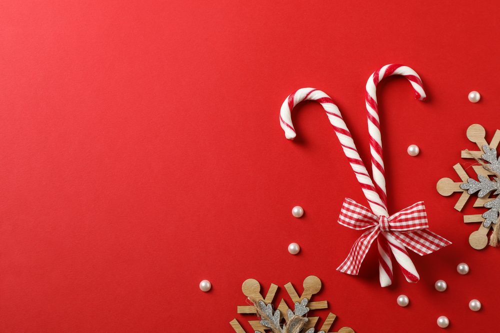 Candy canes and decorative snowflakes on red background, top view