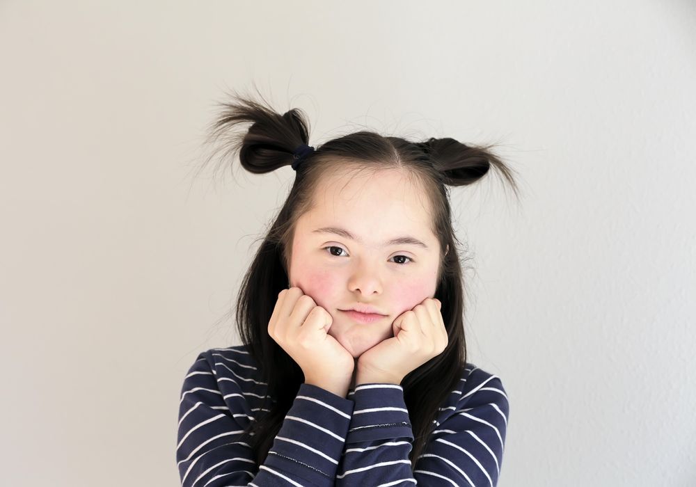 Portrait of young child holding her hands to her chin