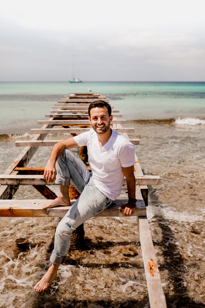 Content male relaxing on old wooden pier on seashore