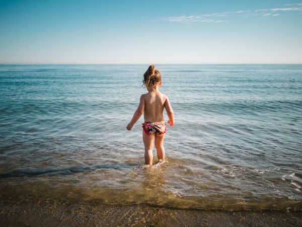 Back view of girl standing in water of seaside