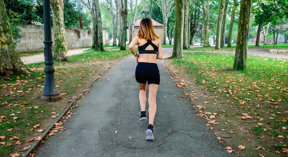 Female athlete running through a park