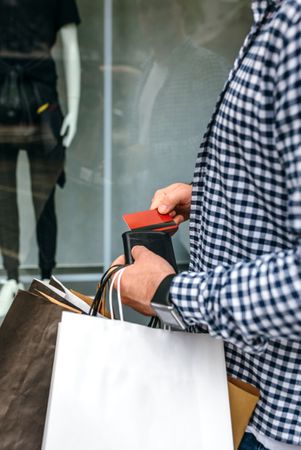 Man taking out credit card in front of shop