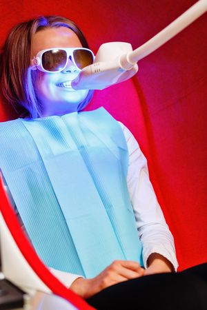 Female in protective glasses and bib during dental procedure