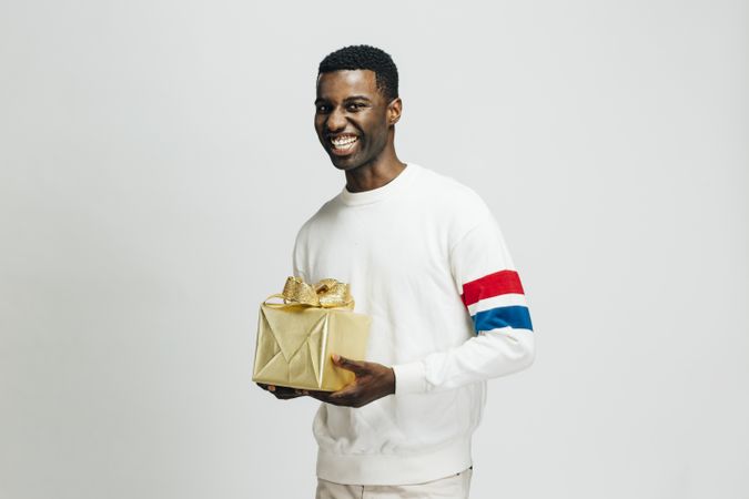 Smiling Black man holding gold box in his hands