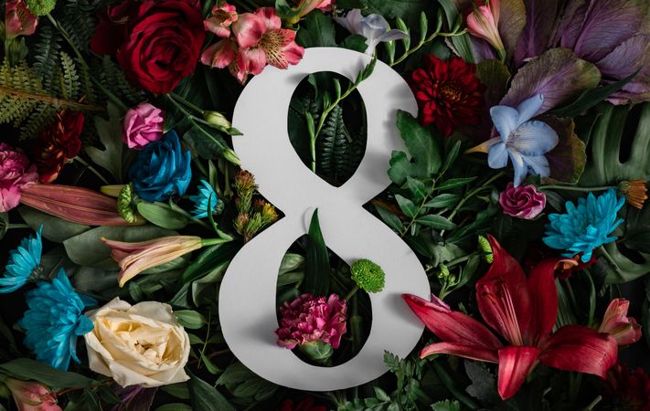 Colorful spring flowers of red, blue, pink, cream around the number “8” on dark background