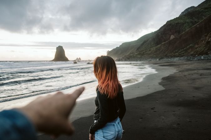Crop man pointing to a girl on the beach
