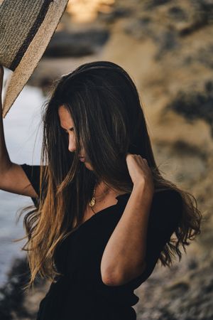 Cheerful woman holding hat in air