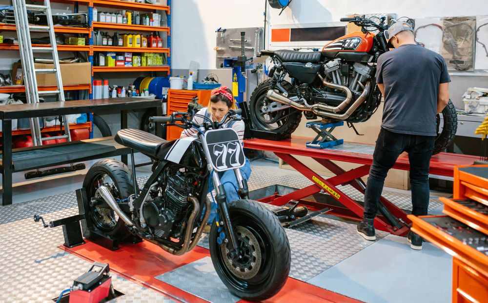 Mechanic couple repairing custom motorcycles on factory