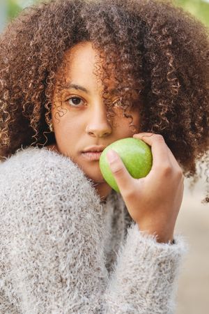 Curly haired Black woman with apple