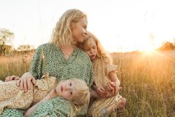 Calm mother embracing daughters in sunlight