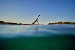 Sportswoman taking Downward Facing Dog pose with leg raised on p