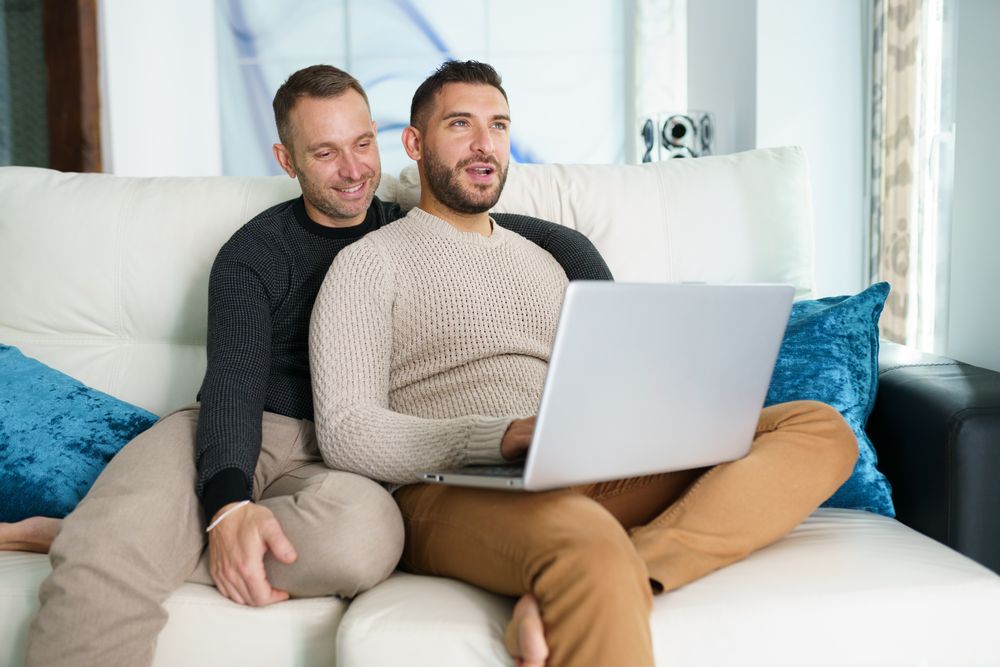 Two men relaxing on couch with laptop