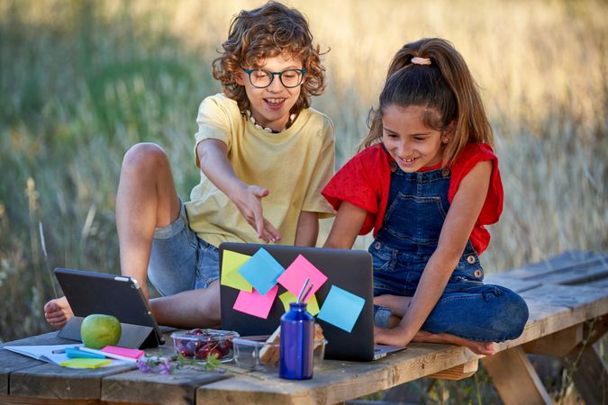 Smiling friends watching funny movie on laptop in park
