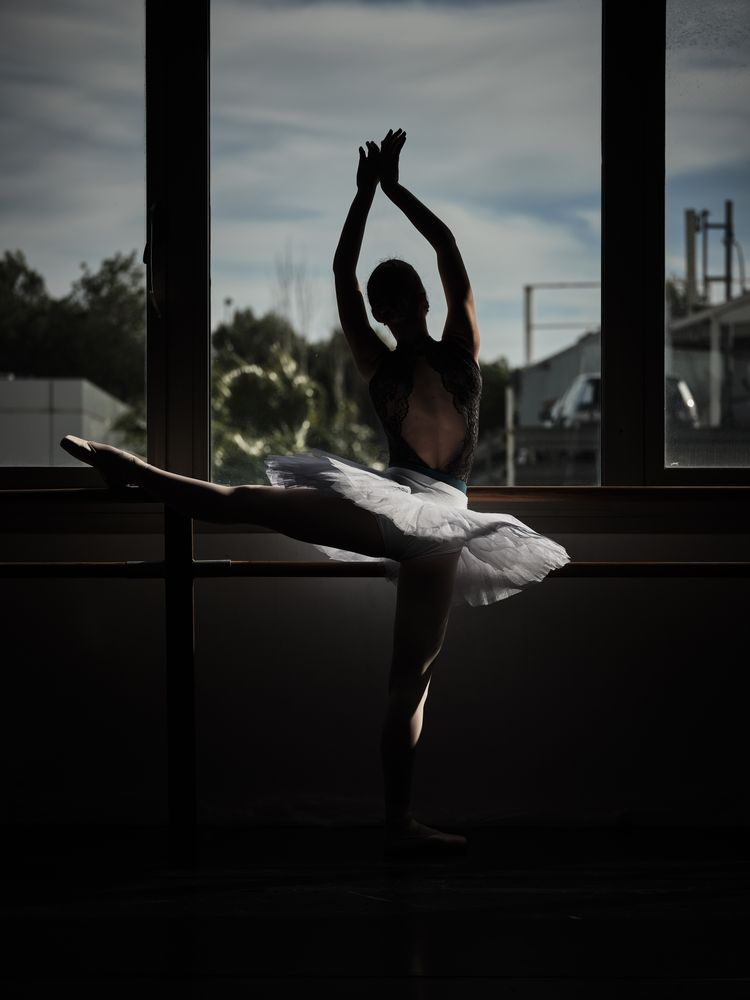 Ballerina doing ballet stretching exercise on barre