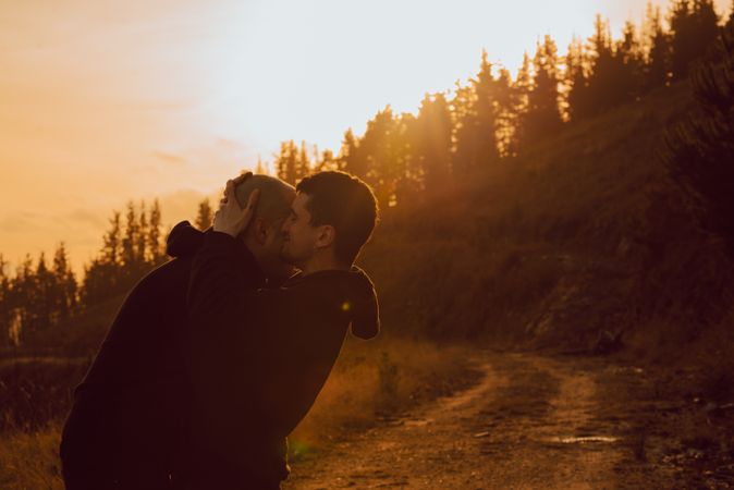 Men hugging and kissing in forest