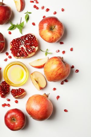 Vertical shot looking down at fresh apples and pomegranates with honey on side