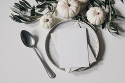Top view of ceramic plate with blank invitation surrounded by ornamental pumpkins
