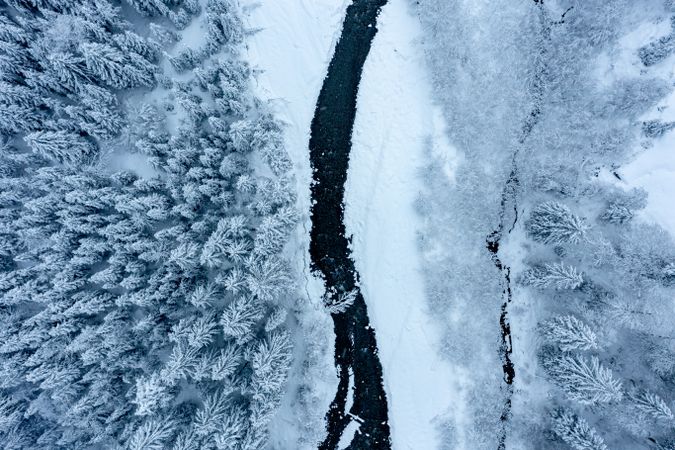 Drone aerial image with snowy forest and river in the Bavarian Alps, Germany