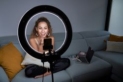 Woman applying lipstick while streaming in social media on smart