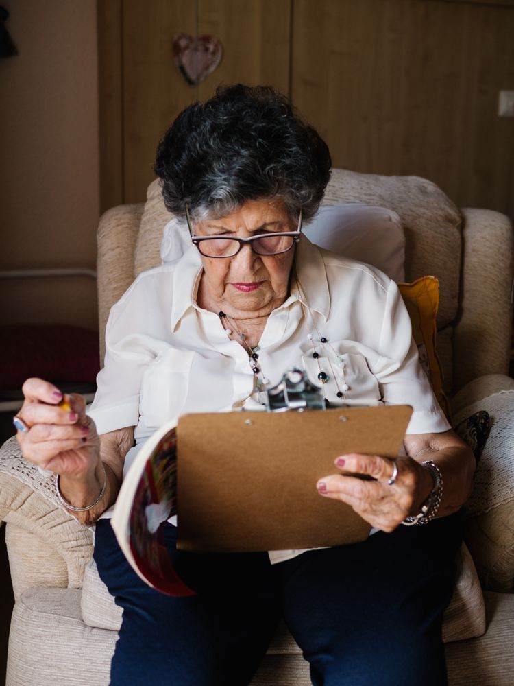 Mature woman solving crosswords in apartment