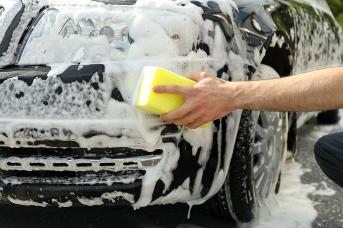 Man wipes the car with a sponge. Car wash. Clear car concept