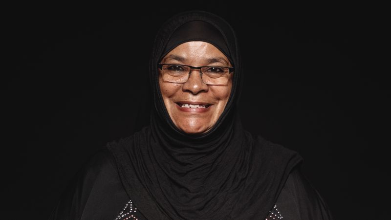 Close up of a smiling muslim woman in hijab isolated on dark background