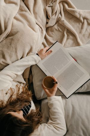 Person reading a book on the bed