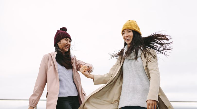 Two happy young women holding hands in winter