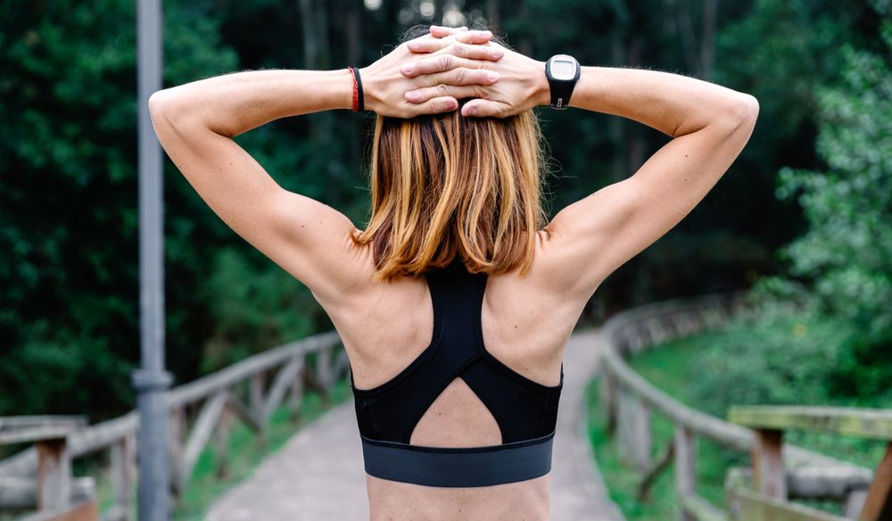 Unrecognizable sportswoman doing stretching arms outdoors