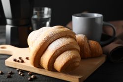 Composition with croissants on wooden breadboard, top view