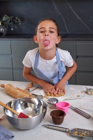 Girl showing tongue while cooking in kitchen