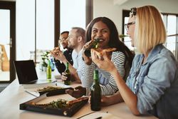 Multi-ethnic group of colleagues enjoying a slice of pizza after work together