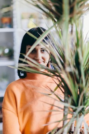 Woman's face behind leaves of big plant.