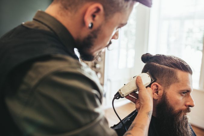 Barber trimming man’s hair with clippers