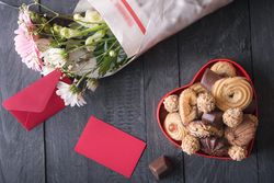 Top view of blank red message card and  box of sweets on rustic table