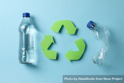 Glass and plastic water bottle with recycling symbol in blue room 479nl0